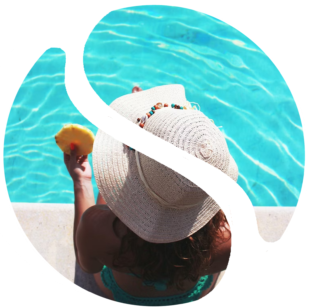 A woman in white hat holding an orange near the pool.